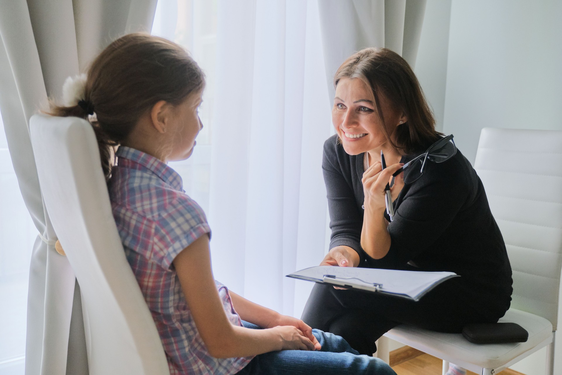 Mujer maestra de escuela primaria probando hablar con la niña